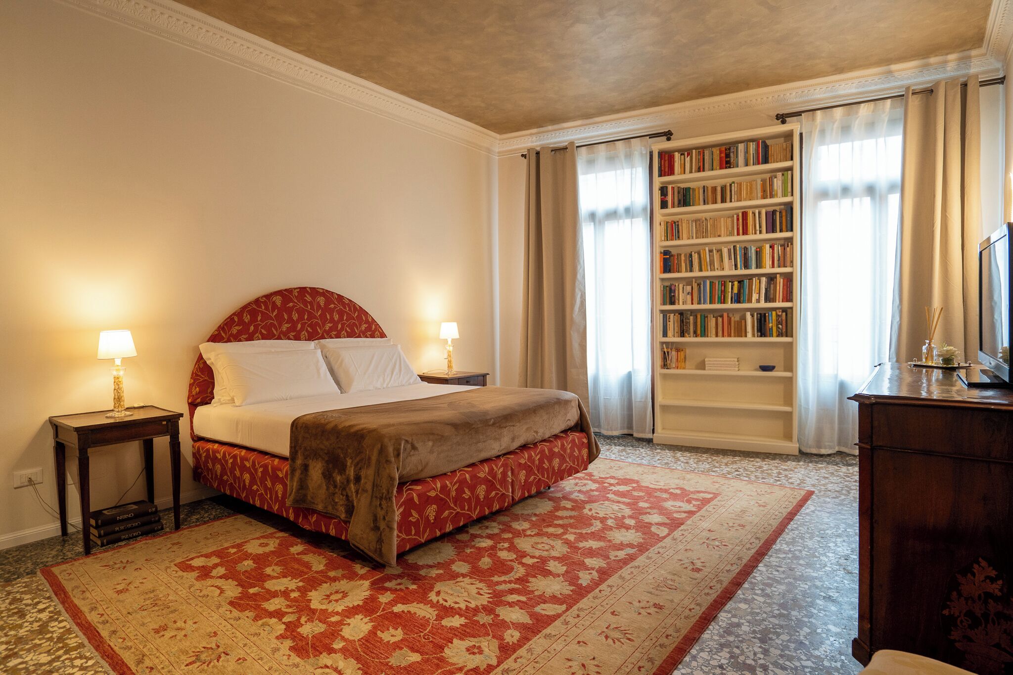 A bedroom with a large bed, a bookshelf, and a desk.