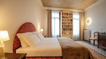 Une chambre d’hôtel bien aménagée, avec un grand lit, une bibliothèque, un bureau et une chaise.
