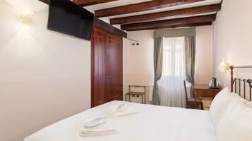 Une chambre d’hôtel équipée d’un lit, d’un bureau, d’une chaise, d’une télévision et d’une fenêtre avec des rideaux.