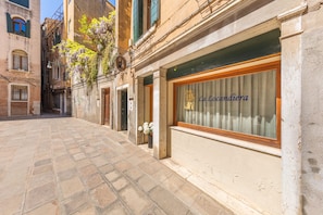 A narrow street with a building featuring a large window with the inscription "La Locandiera". - La Locandiera (Venice)