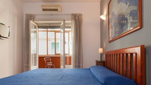 Ein Hotelzimmer mit einem großen Bett, einem Fenster mit Vorhängen, einer Karte an der Wand und einem kleinen Tisch mit einer Lampe.