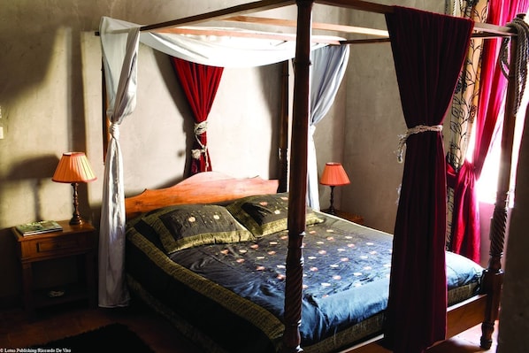 A four-poster canopy bed with red and white drapes, two bedside tables with lamps, and a floral-patterned bedspread. - Hôtel de Digoine - Demeure d'hôtes (Bourg-Saint-Andeol)