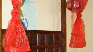 Una cama con un colcha de colores, un cabecero de madera y cortinas de dosel rojas.