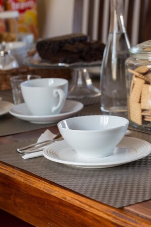 A dining table with white ceramic bowls and plates, a glass pitcher, and a jar of cookies. - Il Bargello (Florence)