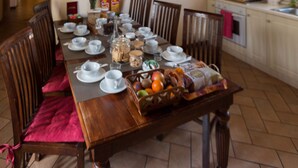 A dining area with a wooden table set for a meal, surrounded by chairs.