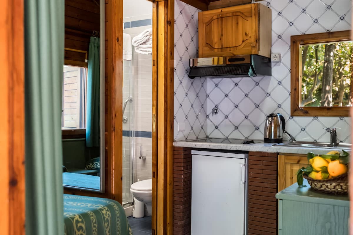 A compact kitchen with a refrigerator, sink, and wooden cabinets.
