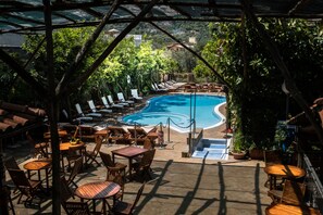 A poolside area with lounge chairs and tables, a pool, and a view of the surrounding landscape. - Villaggio Verde (Sorrento)
