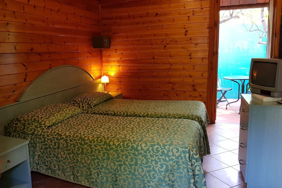 A wooden room with two beds, a TV, and a small table.