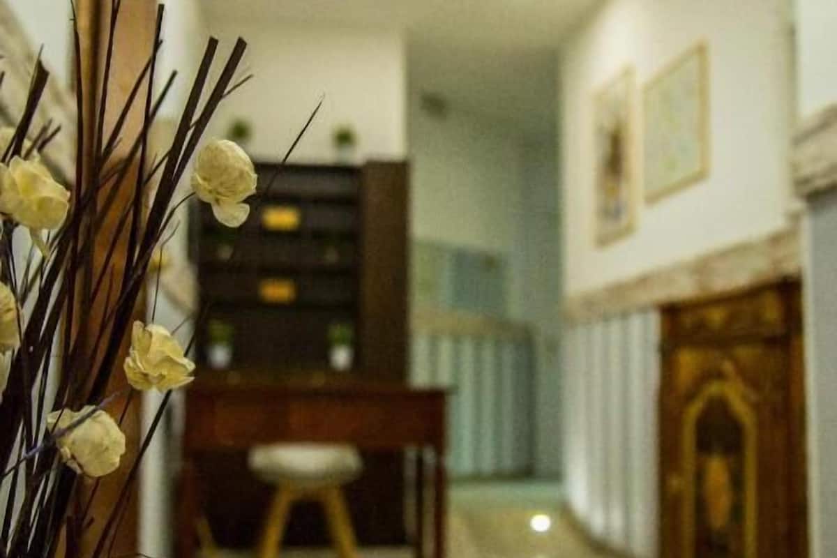 A hallway with a wooden cabinet, a desk, and a vase with flowers.