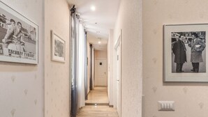 A hallway with framed photographs on the walls, a light wooden floor, and a door at the end. - Marta Inn (Rome)