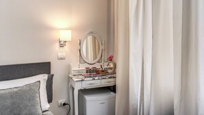A hotel room with a white vanity, a mirror, a small cabinet, and a bed with grey bedding. - Marta Inn (Rome)