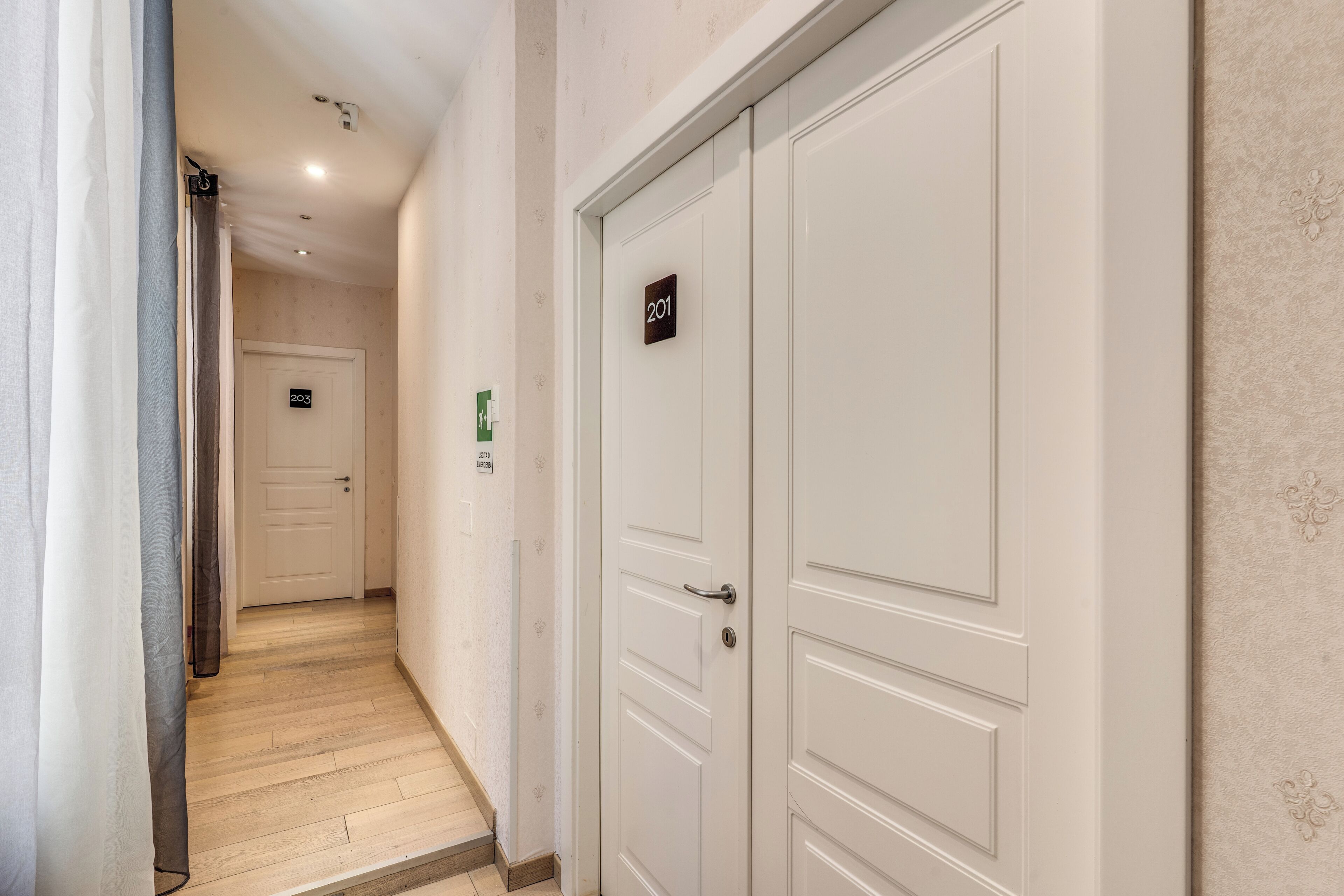 Un pasillo con una puerta blanca marcada '201' y otra puerta marcada '203' en un hotel.