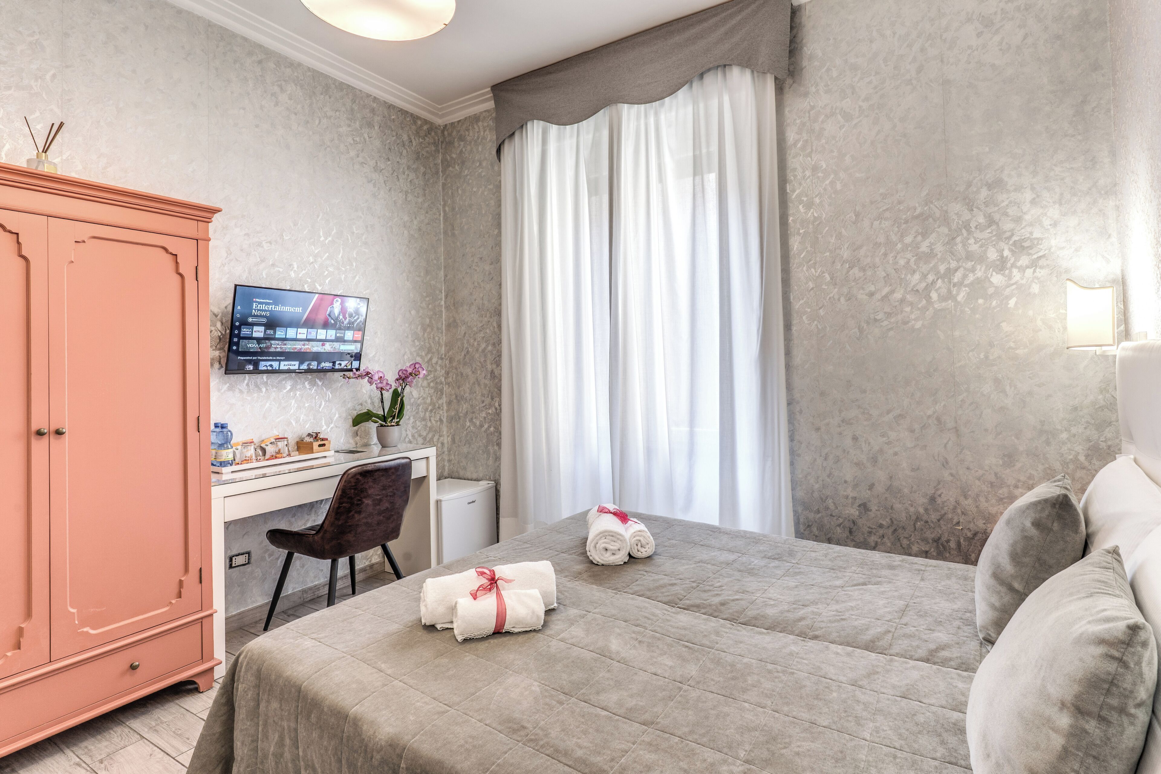 A hotel room with a bed, a desk, a television, and a wardrobe.