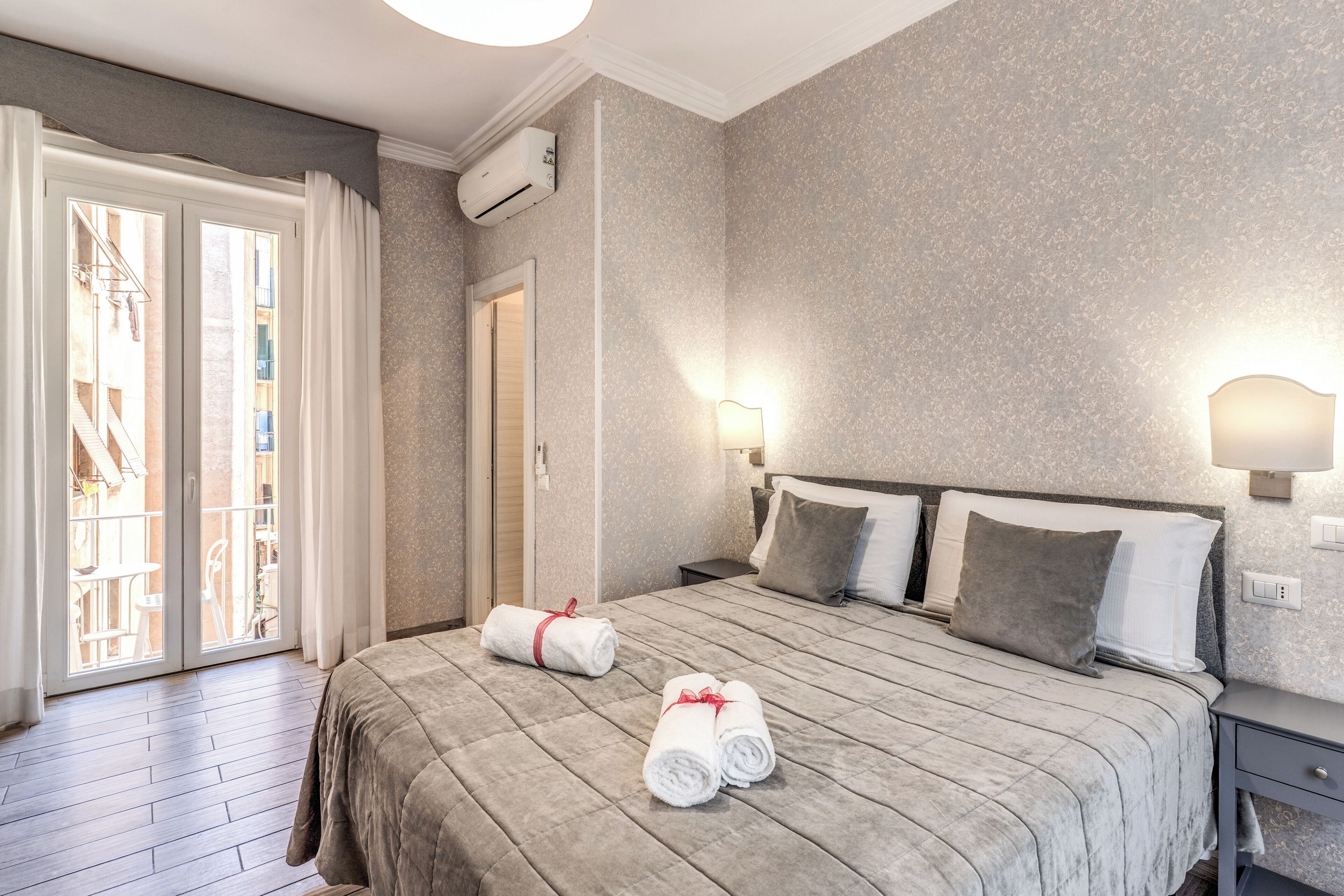 Une chambre d’hôtel comprenant un lit, deux lampes de chevet, une table de chevet, une fenêtre avec des rideaux et un appareil de climatisation.