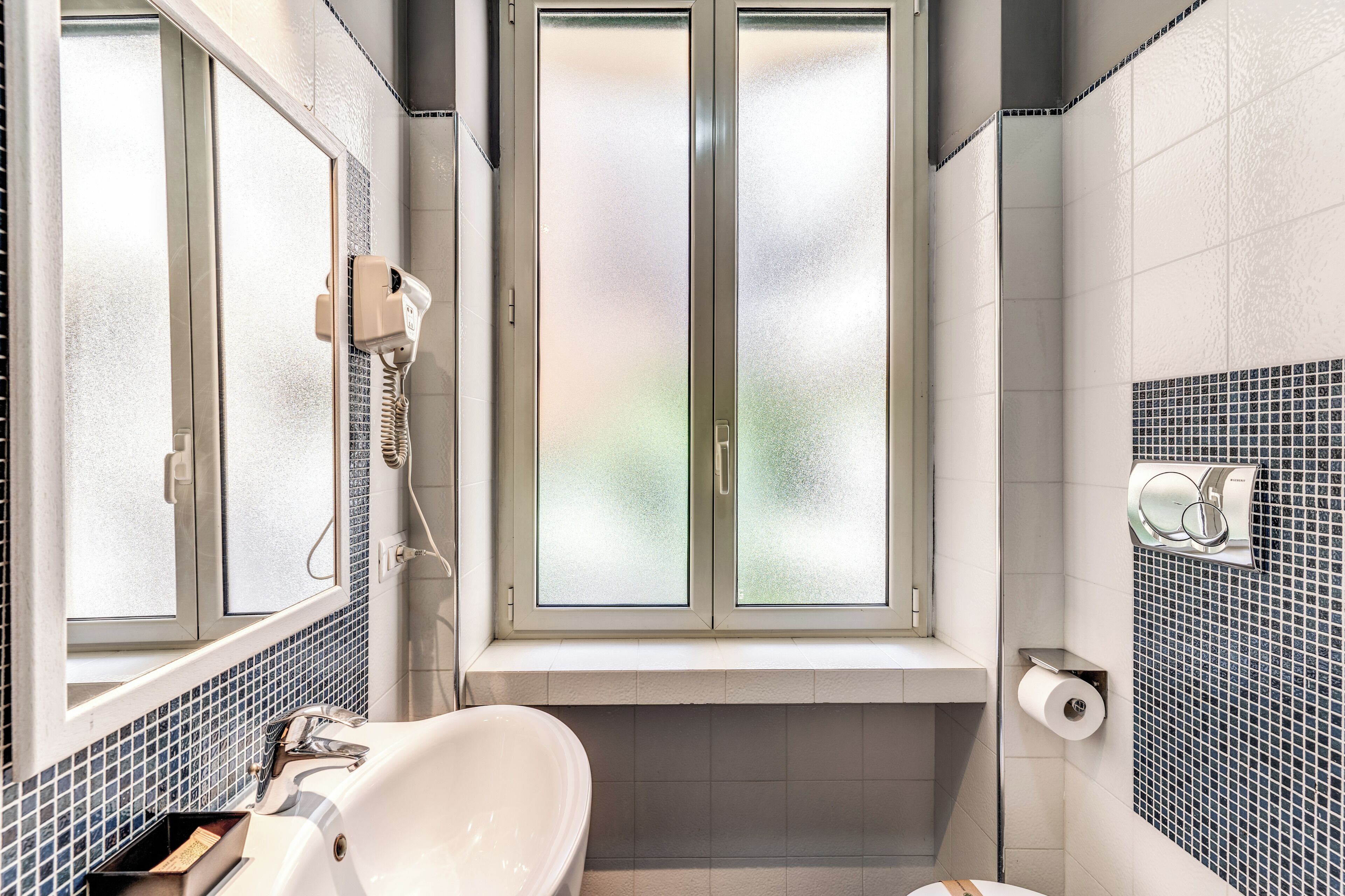 A bathroom with a large window, a bathtub, a sink, and a toilet.