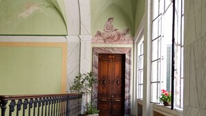 Un vaste hall avec un sol en marbre, une porte en bois et une grande fenêtre ornée de fleurs.