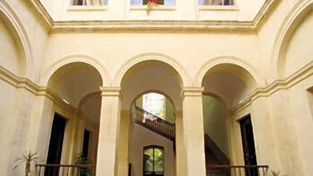 Un bâtiment doté d’une cour intérieure, d’entrées en arc de cercle et d’un escalier menant à un étage supérieur.