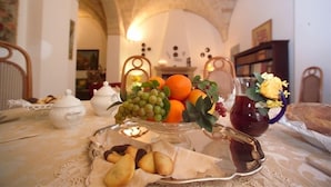 Une table sur laquelle sont disposés des fruits et des biscuits, une théière et un pichet de thé, dans une pièce dotée de plafonds en arc de cercle et d’une bibliothèque.