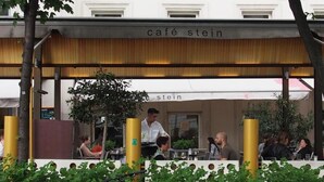 An outdoor café with tables and chairs, surrounded by greenery and yellow pillars. - Pension Liechtenstein (Vienna)