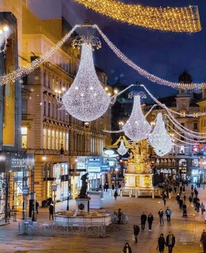 A public square with illuminated structures and a statue. - Pension Liechtenstein (Vienna)