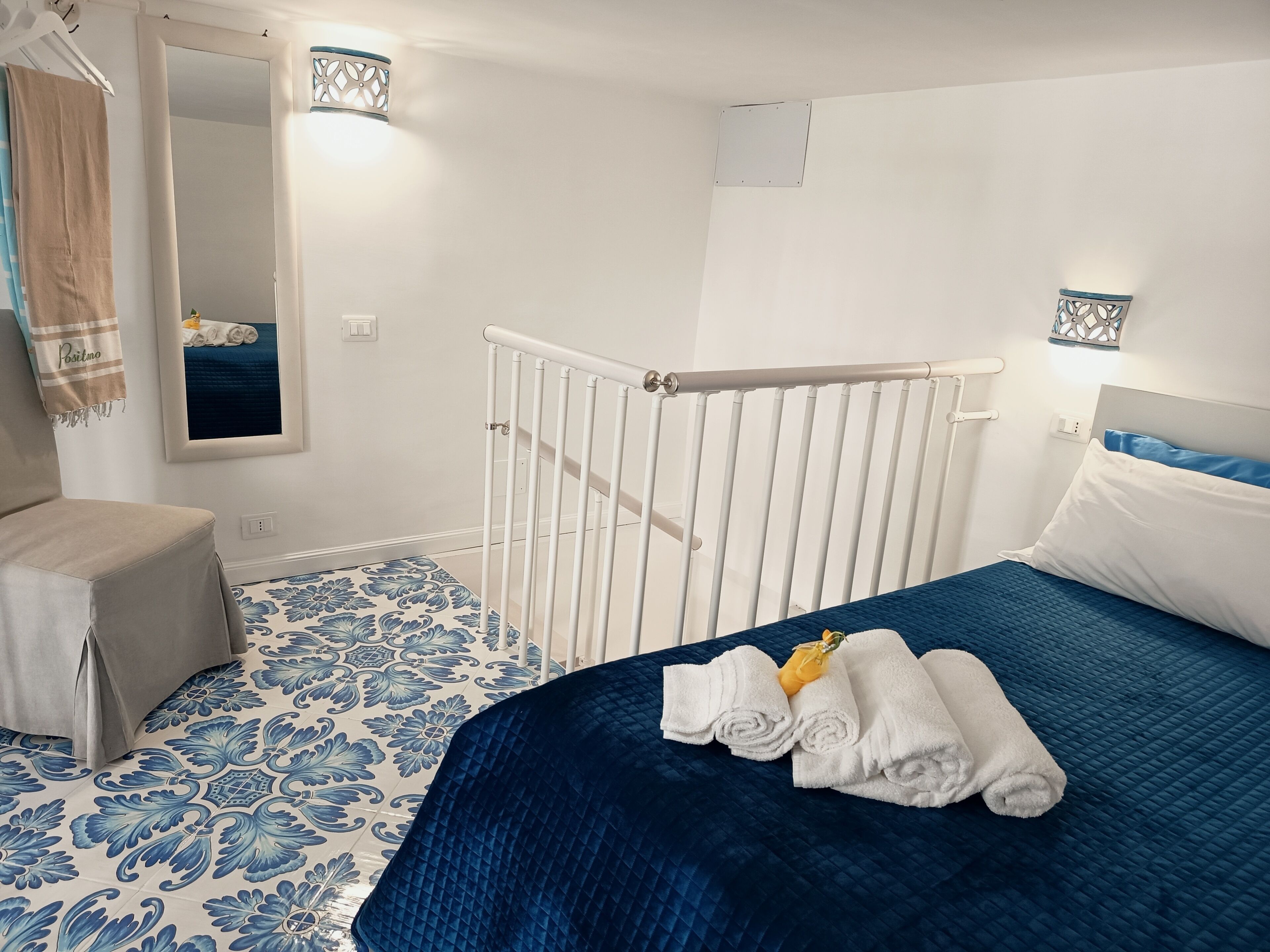 Hotellihuone, jossa on sänky, tuoli, peili ja kuviollinen lattia.