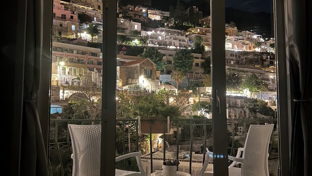 Ein Balkon mit Blick auf eine Stadt am Hang bei Nacht.