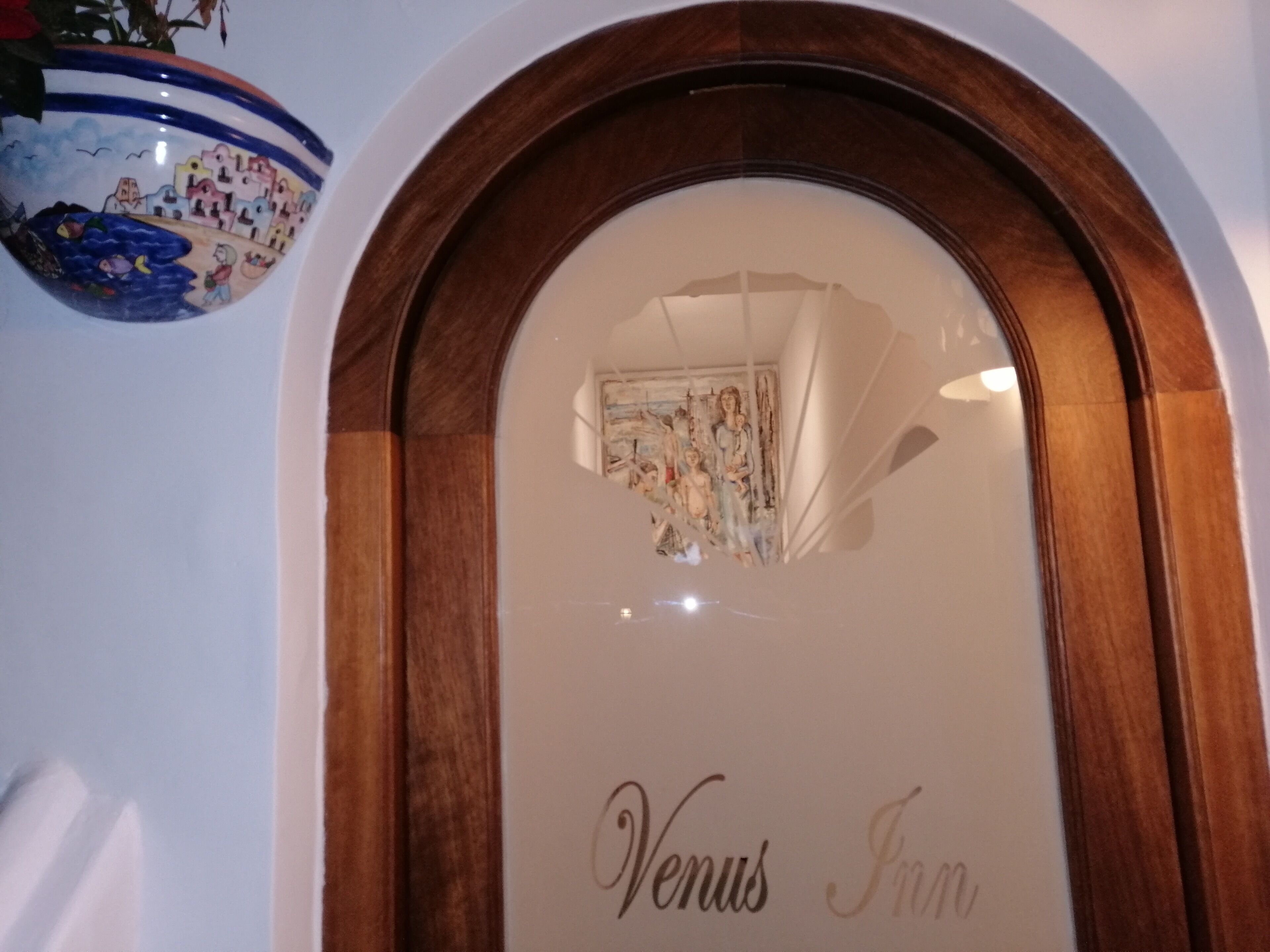 A framed picture with 'Venus Inn' text, a wooden arch, and a decorative bowl with a blue rim.
