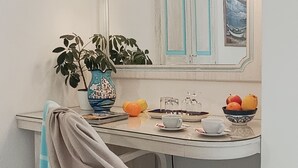 Ein Essbereich mit Tisch, Stühlen, einer Pflanzvase, einer Obstschale und einem Spiegel, der eine Tür widerspiegelt.