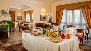 A dining area with a buffet setup, including fruits, pastries, and beverages. - Marini Park Hotel (Rome)