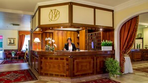 A reception area with a wooden counter, a receptionist, and a check-in desk. - Marini Park Hotel (Rome)