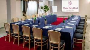 A conference room with a long table, chairs, and a projector screen displaying the hotel's name. - Marini Park Hotel (Rome)