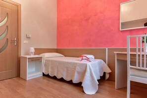 Una habitación con una cama, una mesita de noche, una cuna y un espejo en la pared.