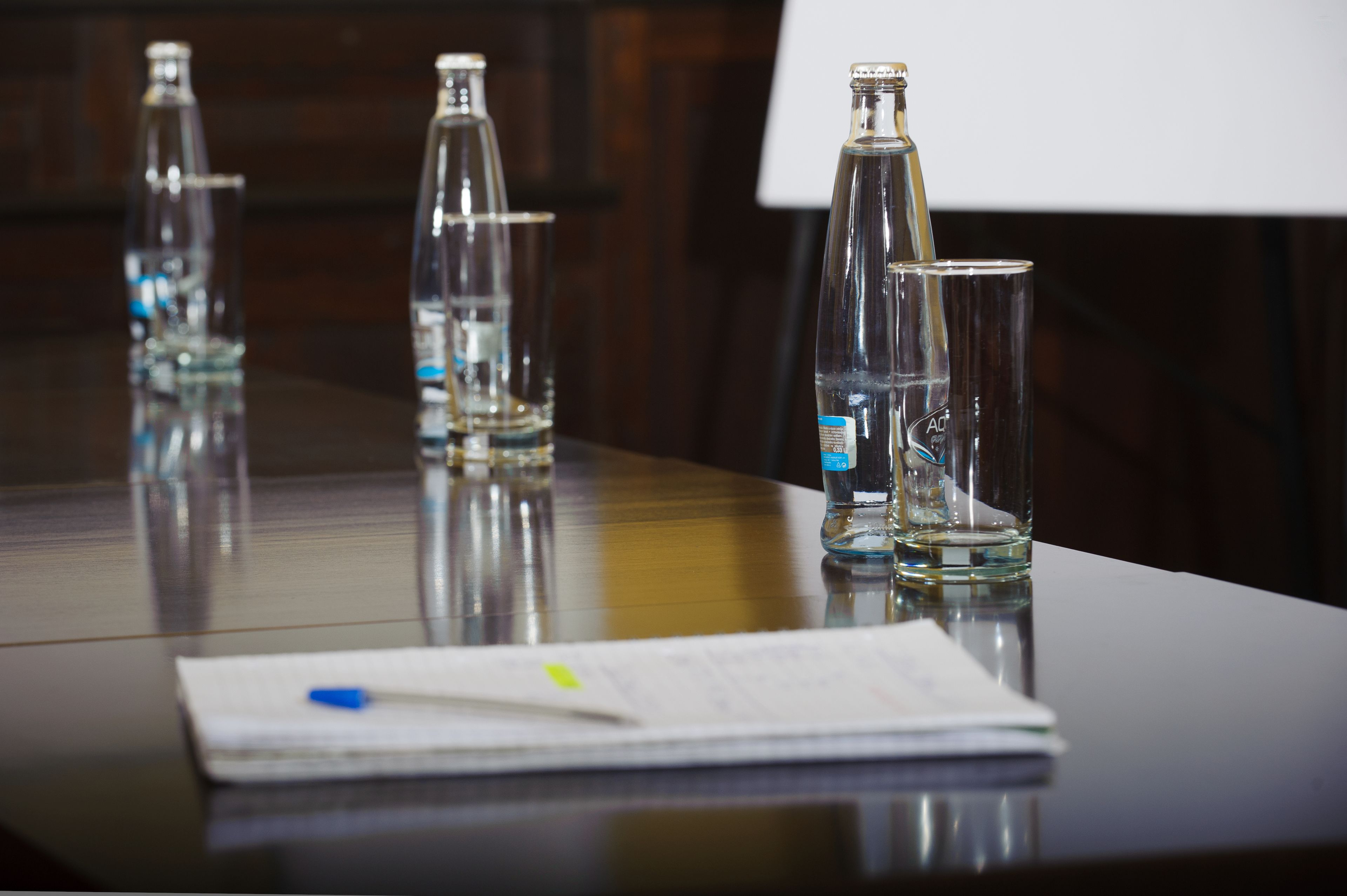 Una mesa con varias botellas de vidrio vacías y un papel con un bolígrafo.