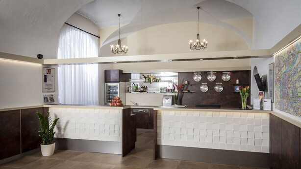 A modern kitchen with a central island, a bar area with a clock, and a large map on the wall. - Hotel Petr (Prague)