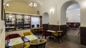 A restaurant with tables and chairs, a display case with items, and a chandelier. - Hotel Petr (Prague)