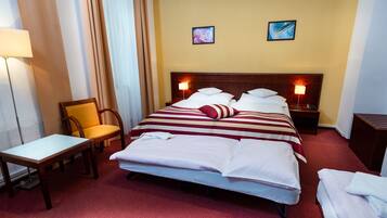A hotel room with a large bed, two bedside tables with lamps, a chair, and a small table.