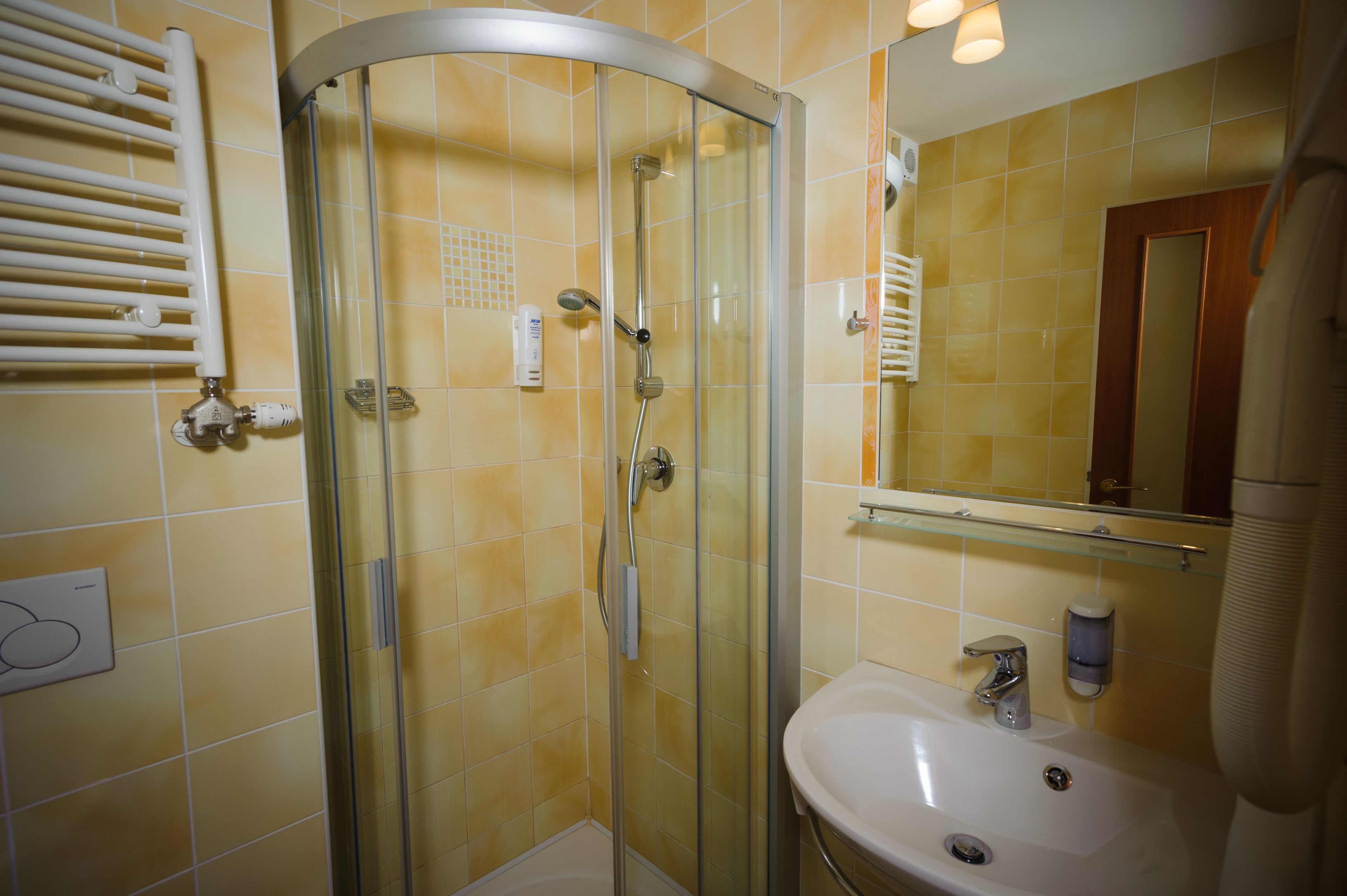 Une salle de bain avec une douche à parois de verre, un lavabo blanc et un miroir au-dessus du lavabo.