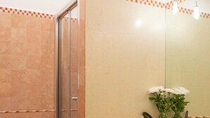 Un baño con mampara de vidrio, lavamanos e inodoro.