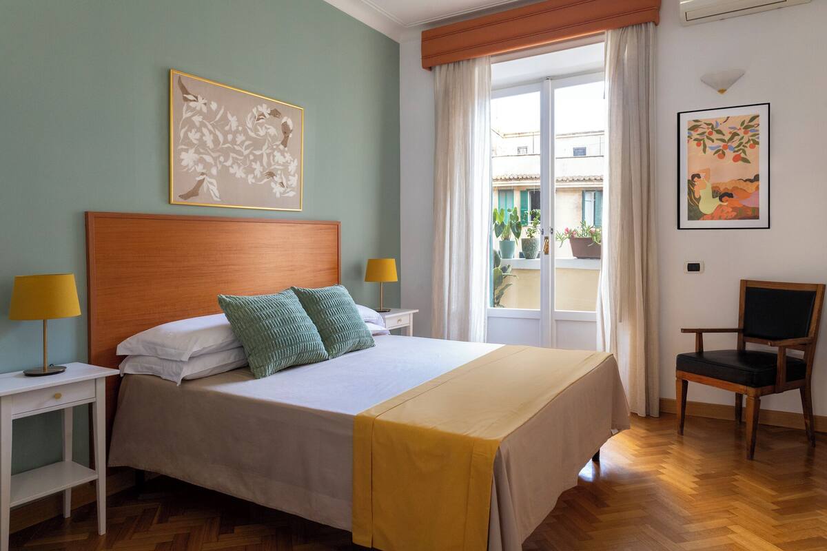 A hotel room with a bed, two bedside tables with lamps, a chair, and artwork on the walls.