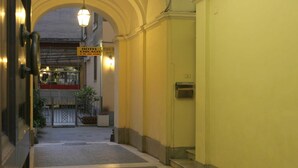 A hotel entrance with a reception desk, a sign for the Pensione Chicago, and a staircase leading to the upper floor.