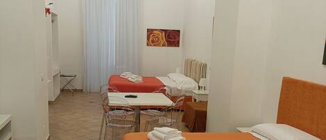 Une chambre d’hôtel avec deux lits, une table à manger, des chaises, un lustre et un tableau au mur.