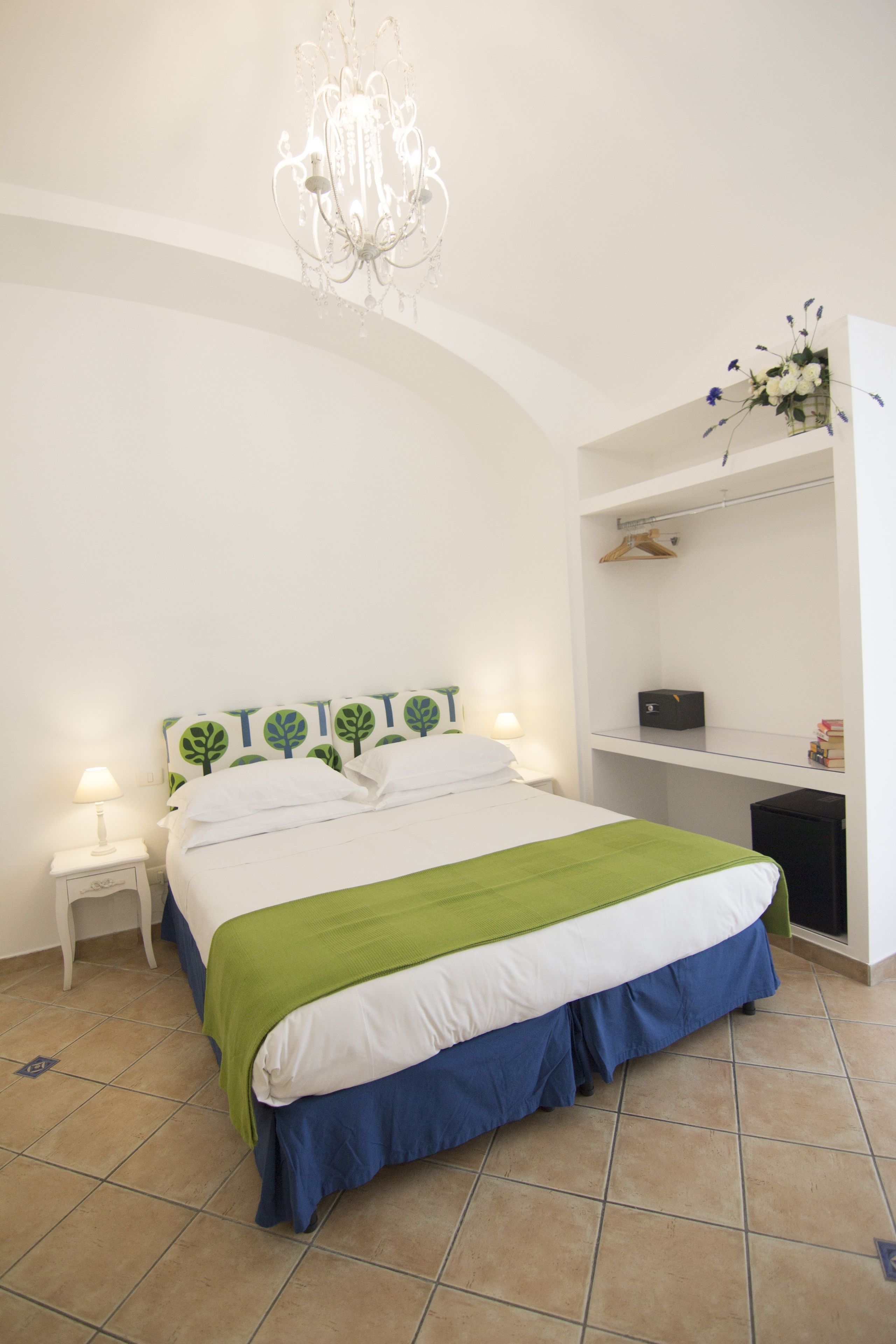 A neatly arranged bedroom with a bed, bedside tables, a dresser, and a hanging light fixture.