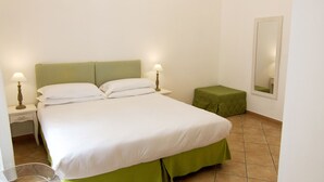 Une chambre à coucher avec un lit, des lampes de chevet, une table de chevet verte, un miroir et un lustre.
