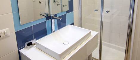 Une salle de bain avec un lavabo blanc, un miroir et une douche à parois de verre.