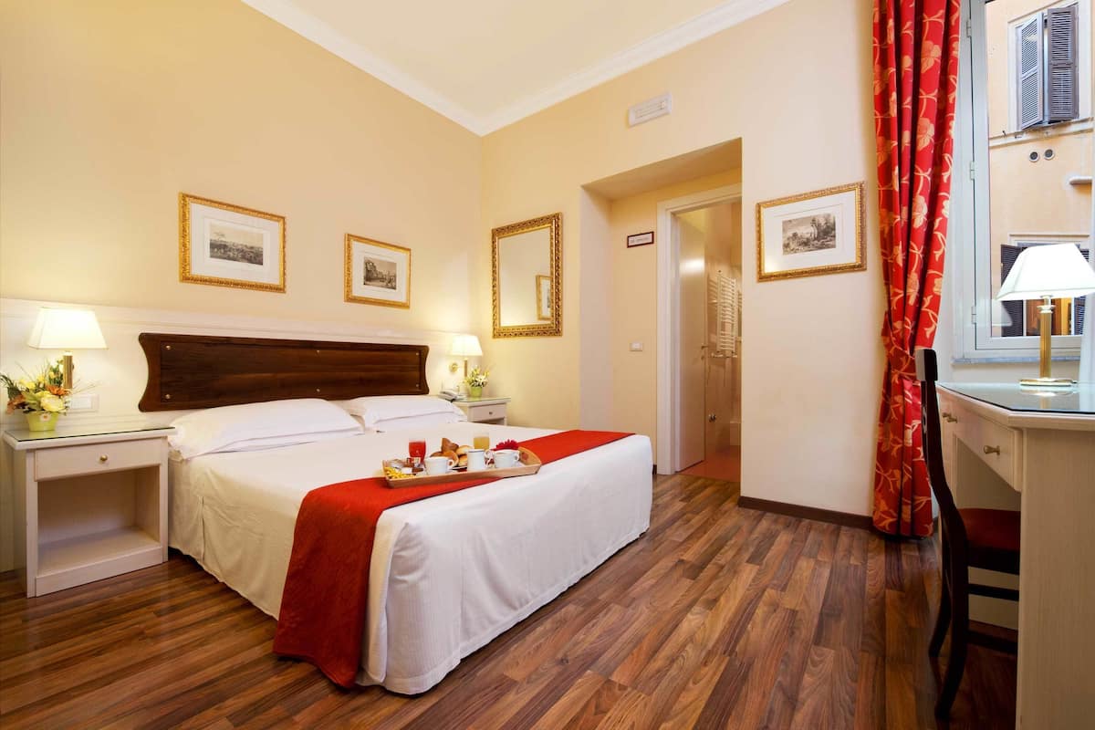 Ein Hotelzimmer mit Bett, Nachttischen, einem Schreibtisch und einem Stuhl.