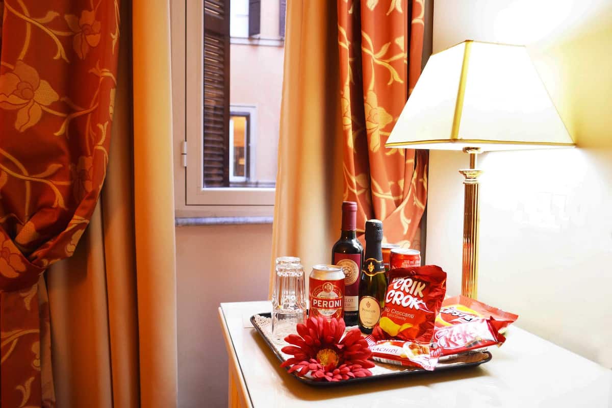Ein Hotelzimmer mit einem Tisch, gedeckt mit einer Auswahl an Snacks, einer Weinflasche, einer Bierdose und einem Glas.
