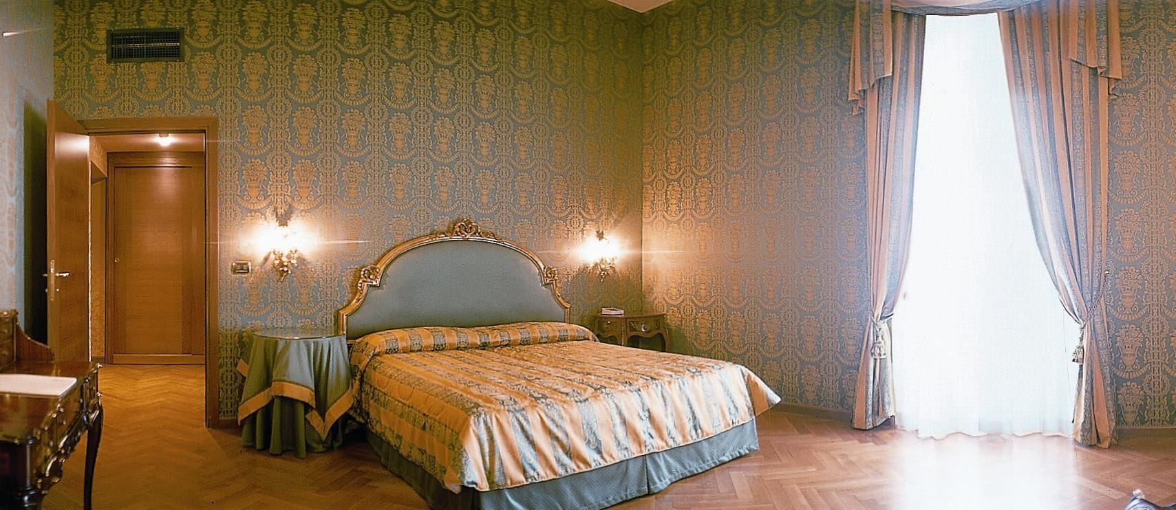 Un dormitorio con una cama grande, dos mesitas de noche, un tocador y un espejo.