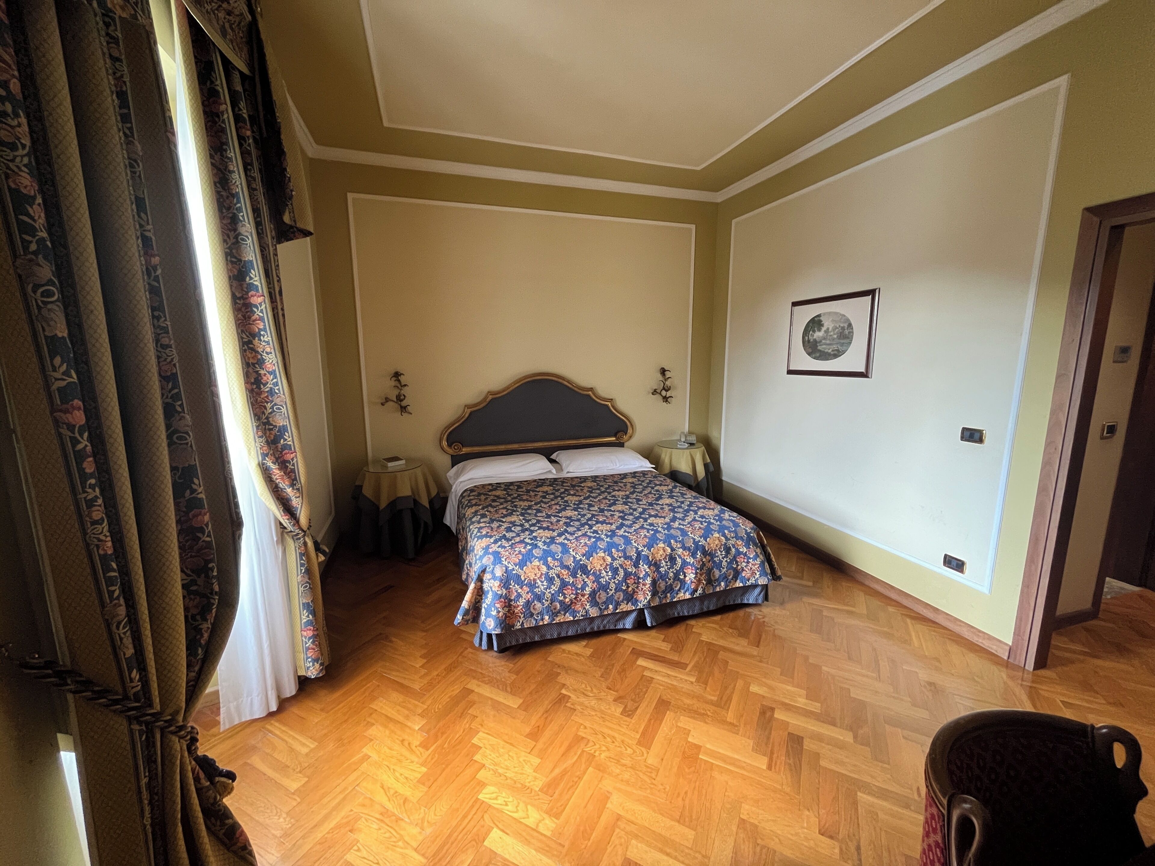 A bedroom with a bed, a small bedside table, a chair, and a door.