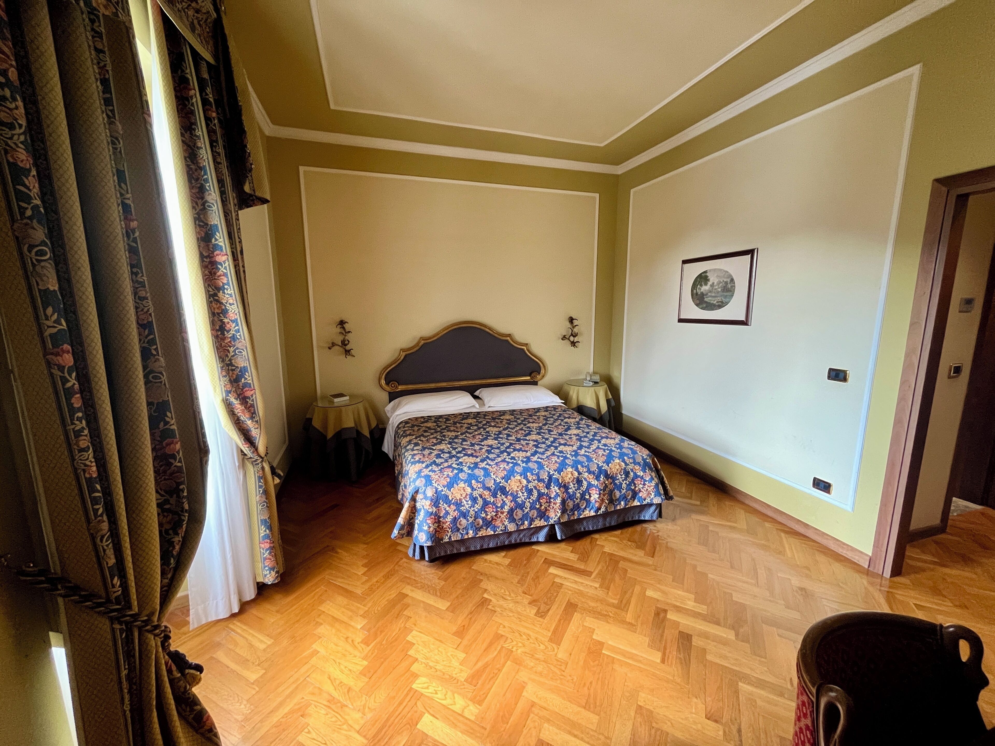 A bedroom with a bed, a small table, a chair, and a door.