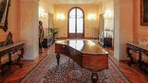 Un amplio pasillo con un gran escritorio de madera, techo ornamentado y un gran arco de entrada.